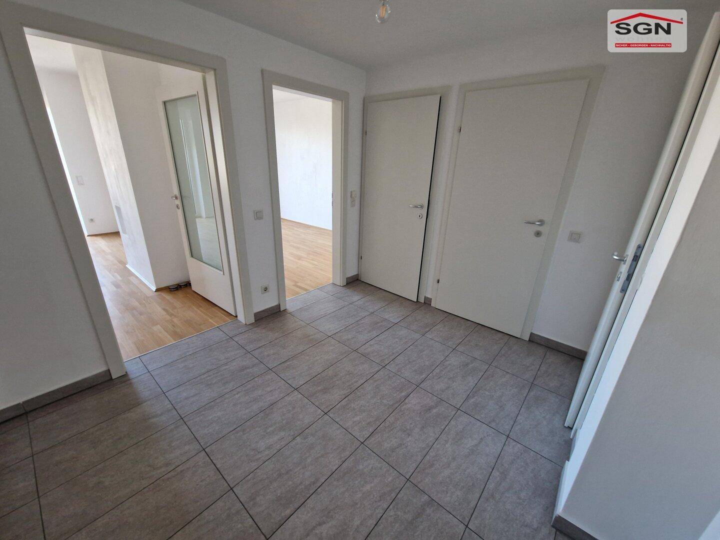 Heller Flur mit Fliesenboden und mehreren Türen, führt zu weiteren Räumen.