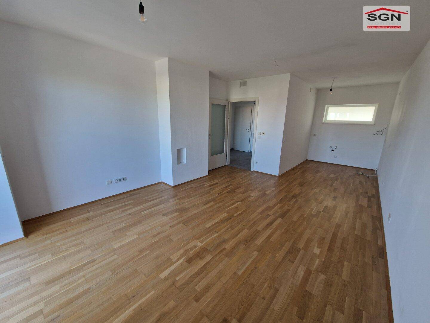 Heller, leerer Raum mit Parkettboden und weißen Wänden, bereit zum Einzug.