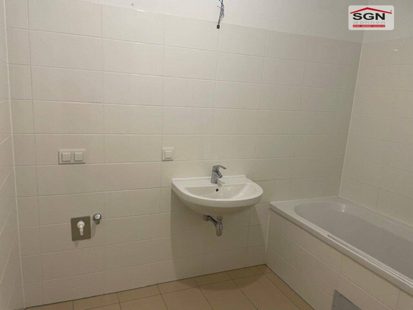 Unmöbliertes Badezimmer mit Badewanne und Waschbecken, bereit zur Einrichtung.