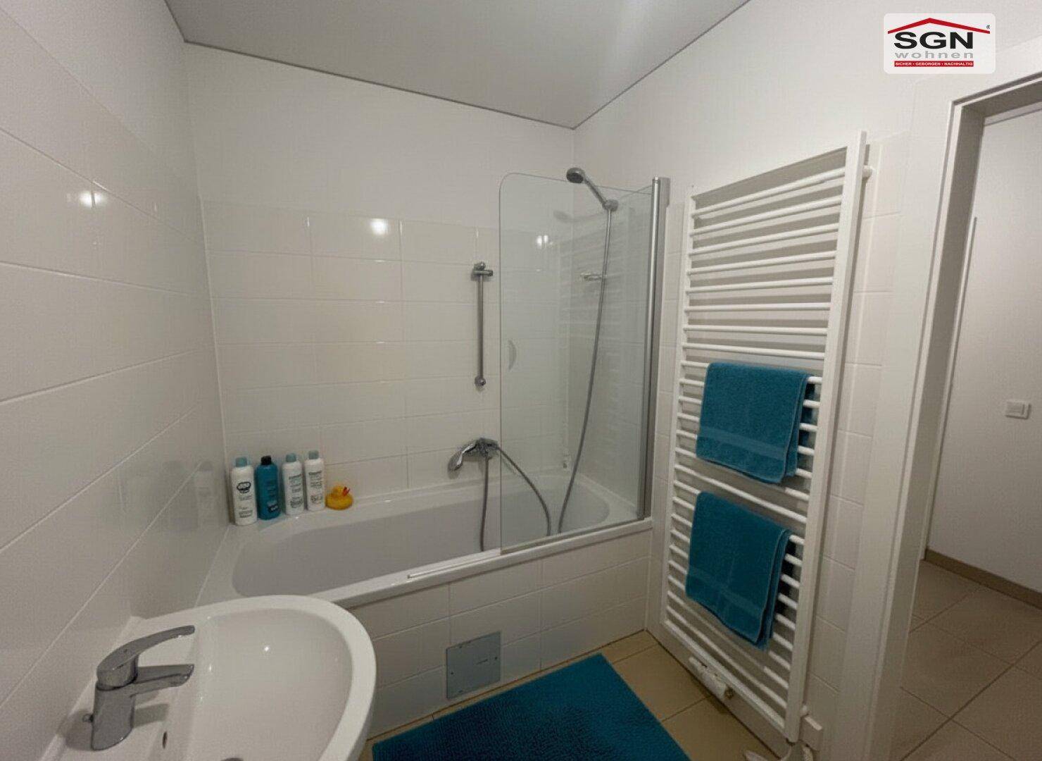 Badezimmer mit Badewanne, Duschabtrennung und beheiztem Handtuchhalter.