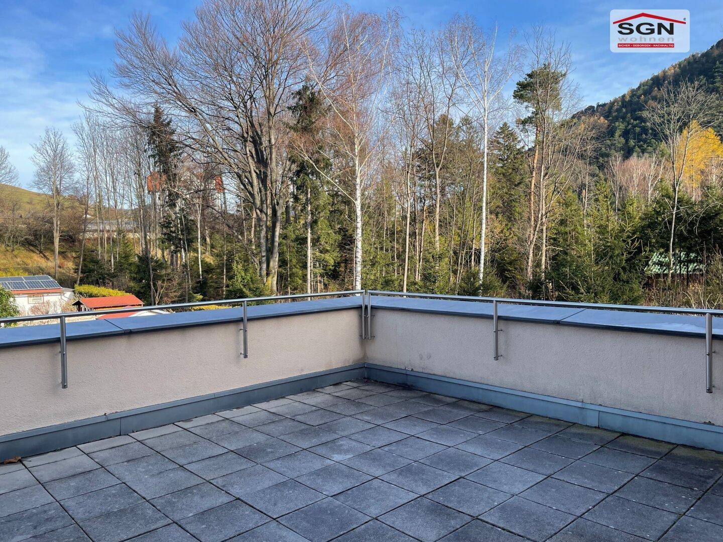 Große, geflieste Terrasse mit Metallgeländer und weitem Blick auf die bewaldete Hügellandschaft.