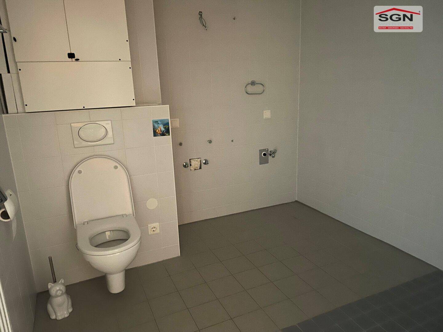 Einfaches WC mit Fliesenboden und Wand-WC, bereit für die Installation weiterer Sanitärobjekte.
