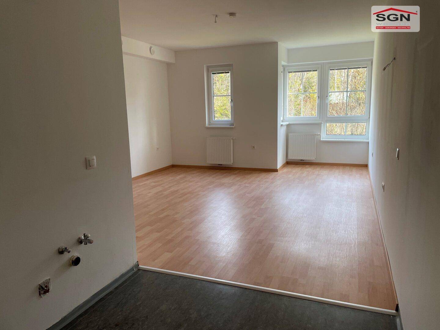 Heller Wohnraum mit Laminatboden und einem vorbereiteten Bereich für Anschlüsse, ideal für eine offene Gestaltung.