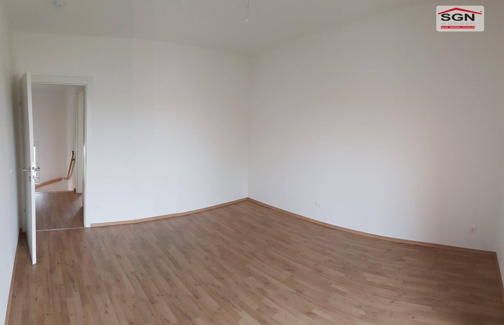 Leeres Schlafzimmer mit Laminatboden und weiß gestrichenen Wänden, bereit zum Einzug.