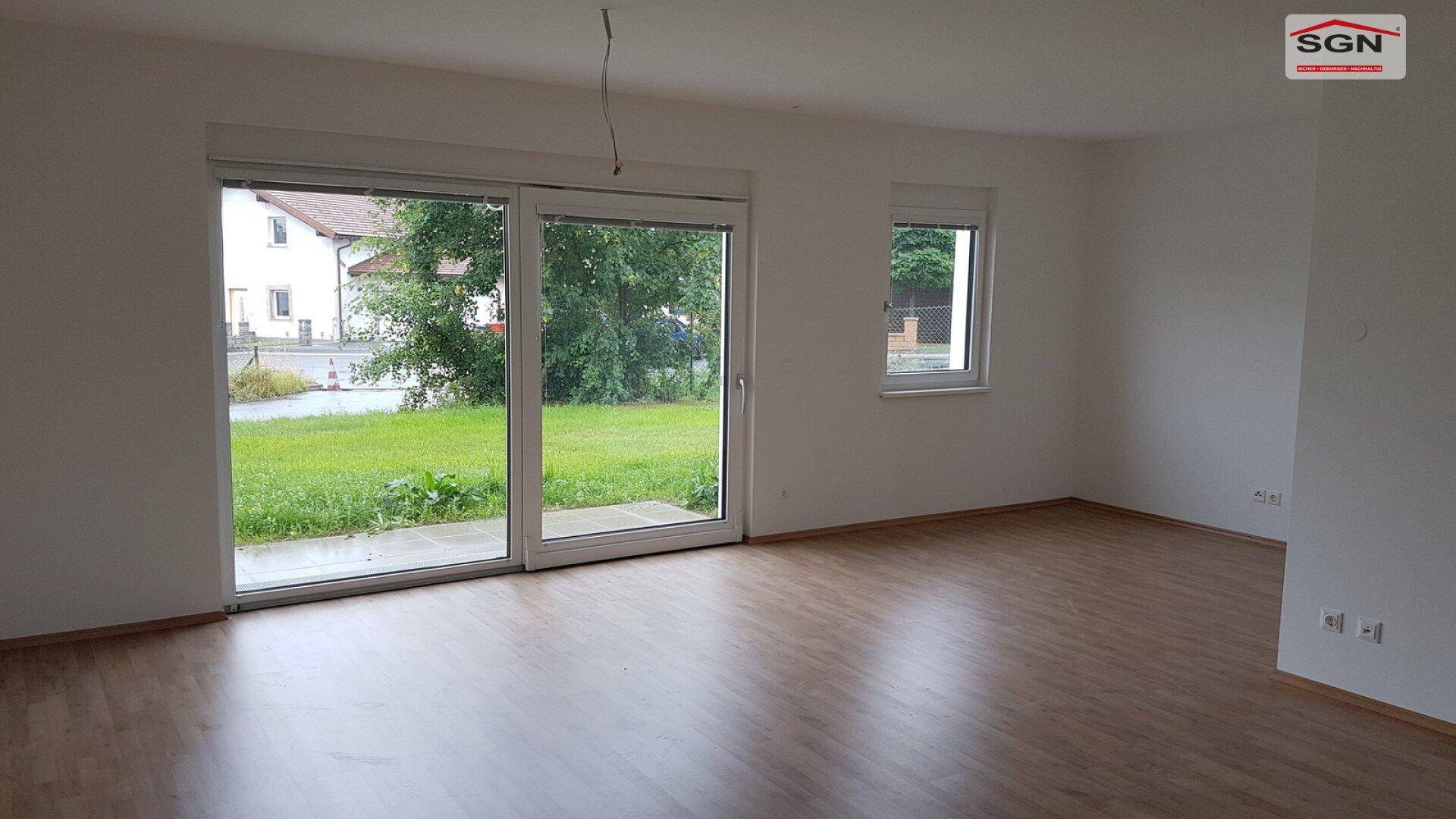 Heller Wohnbereich im Erdgeschoss mit Laminatboden und großem Schiebefenster zum Garten.
