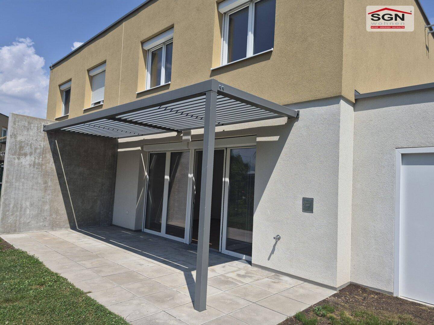 Überdachte Terrasse mit Fliesenboden und Zugang zum Gartenbereich des Hauses.