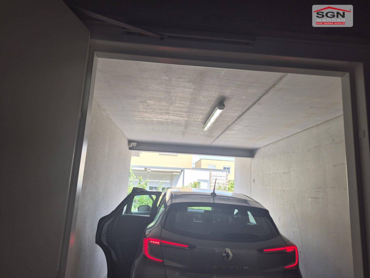 Überdachter Stellplatz oder Garage mit einem geparkten Auto und Blick ins Freie.