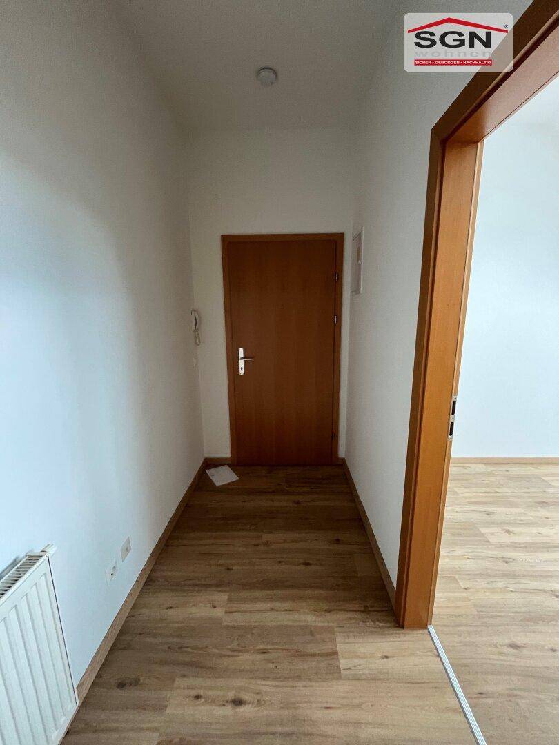 Heller Flur mit Holzboden und Heizkörper, der zu den verschiedenen Räumen führt.