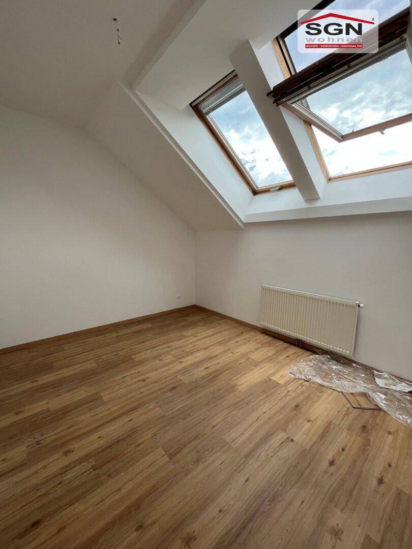Helles Zimmer mit Holzboden, Dachschrägen und großen Dachfenstern, ideal als Schlafzimmer.