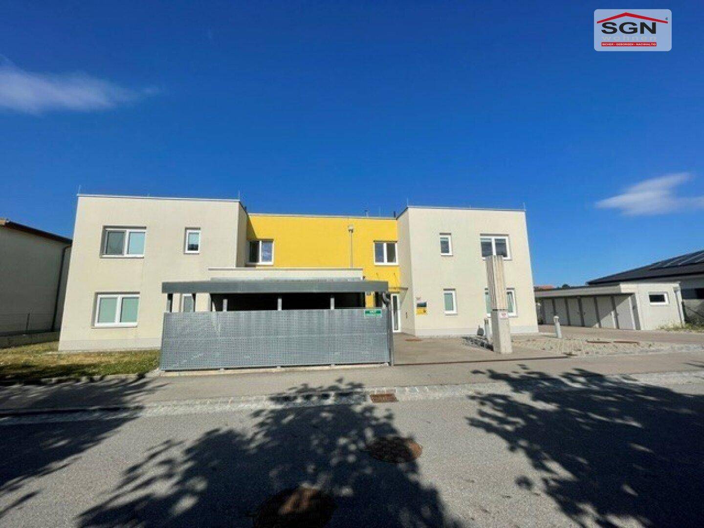 Vorderansicht eines Wohnhauses mit moderner Architektur und gelben Farbakzenten.