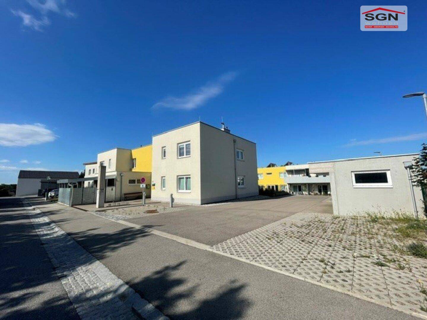 Ansicht eines modernen Wohngebäudes mit gelben Akzenten und Parkplätzen im Freien.