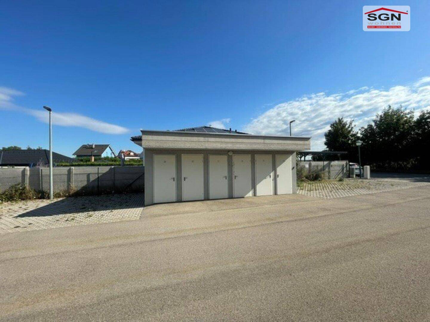 Reihe von Garagen oder Abstellräumen mit Photovoltaikanlage auf dem Dach.