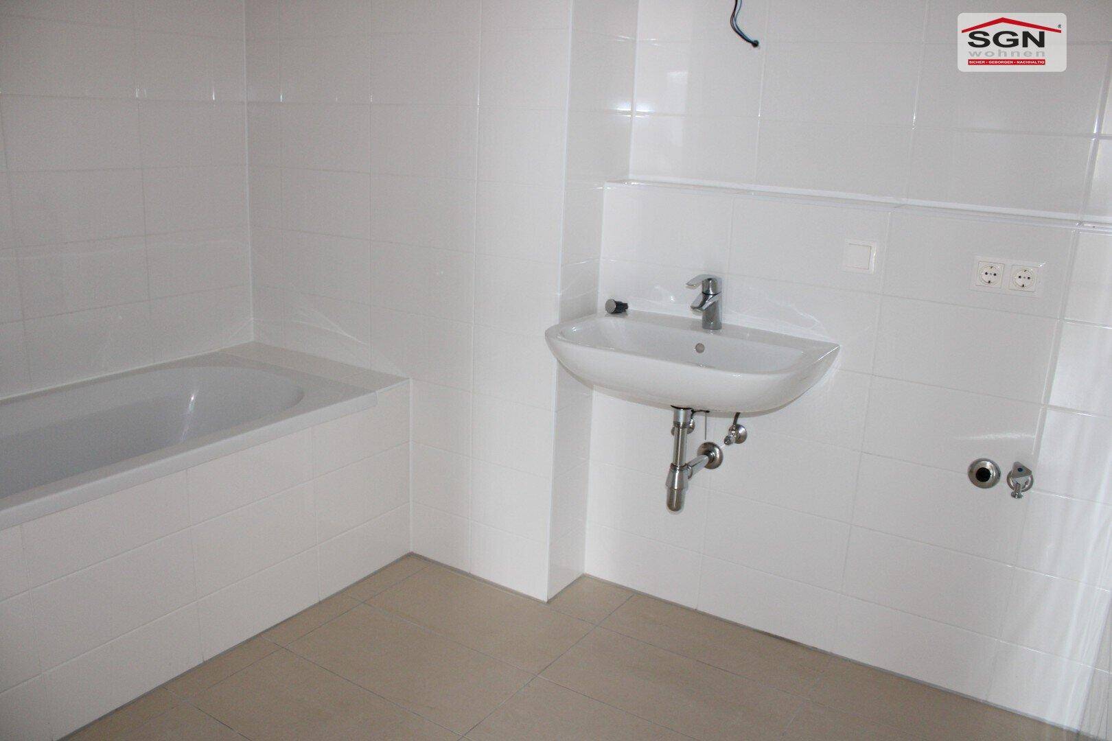 Modernes Badezimmer mit weißen Fliesen, Badewanne und Waschbecken, bereit zur Nutzung.
