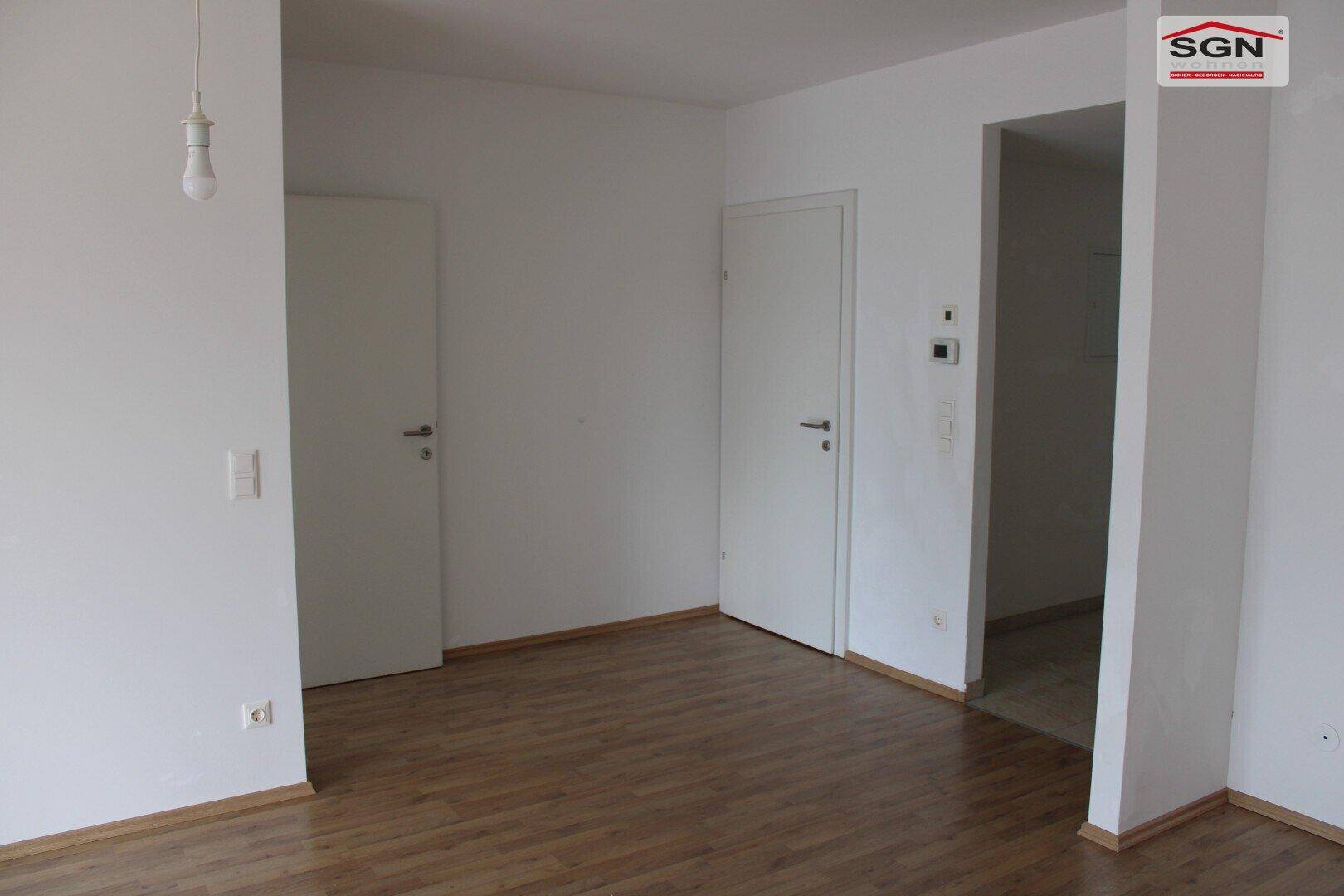 Heller, leerer Raum mit Holzboden und zwei weißen Türen, bietet flexible Nutzungsmöglichkeiten.