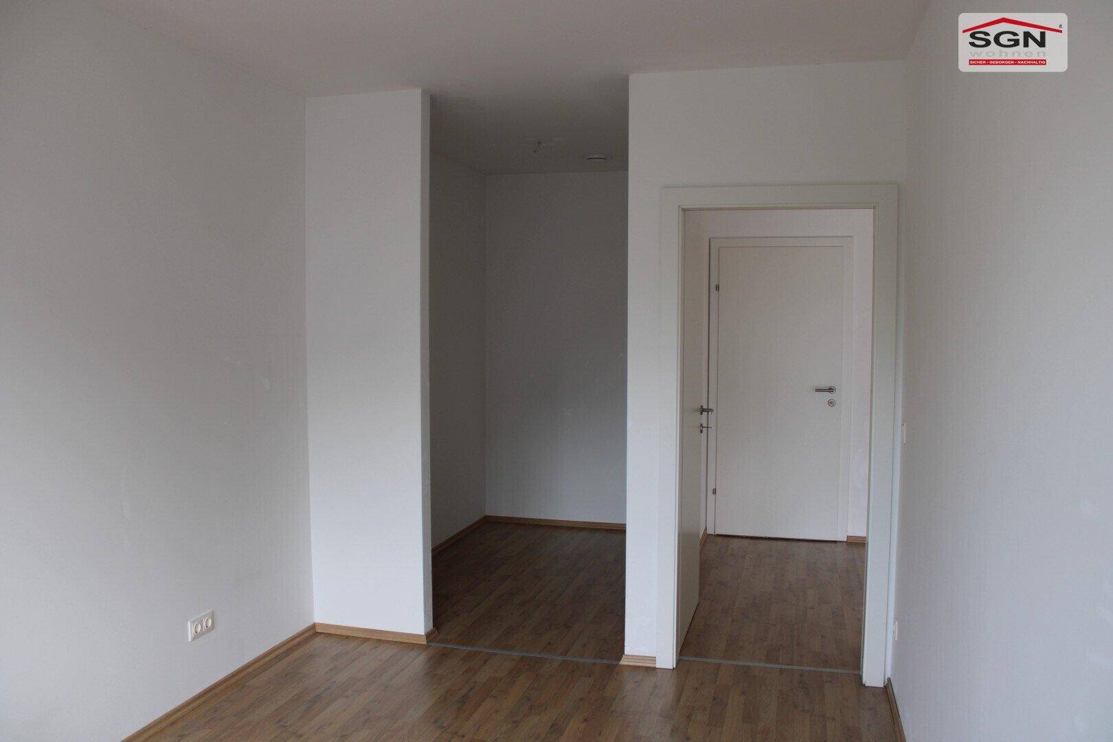 Heller Durchgangsbereich mit Holzboden und weiß gestrichenen Wänden, verbindet zwei Räume.