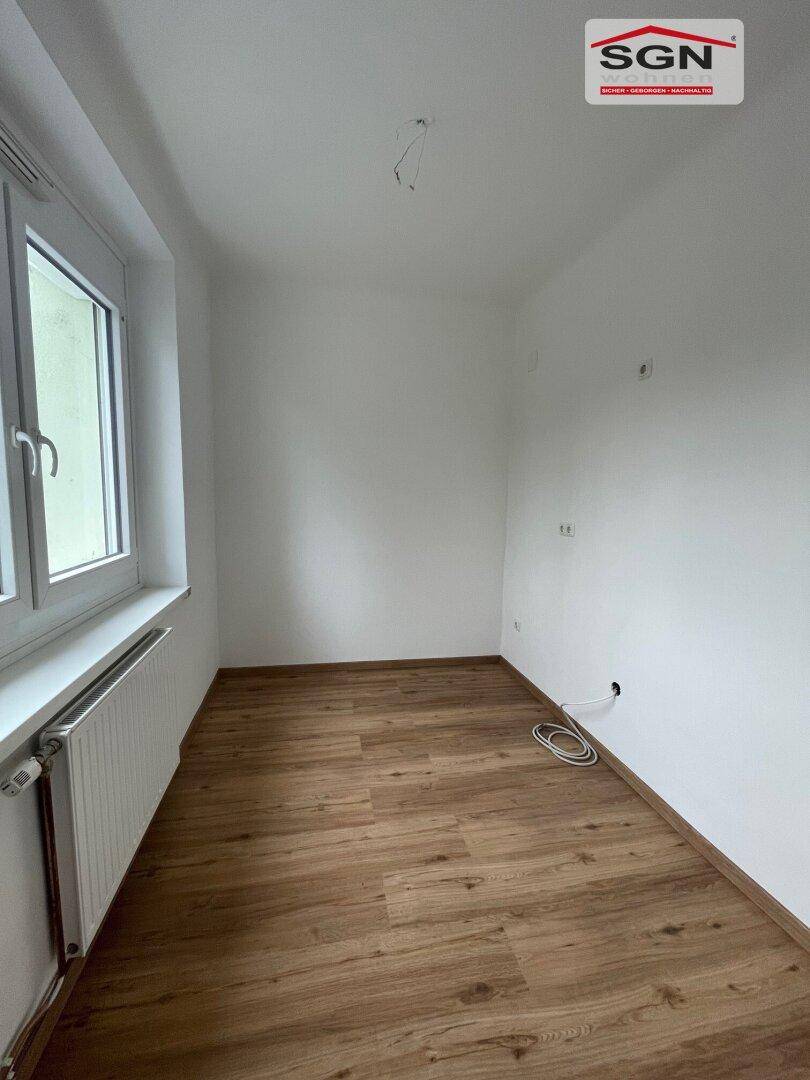 Kleineres Zimmer mit Laminatboden, weiß gestrichenen Wänden und einem Fenster, vielseitig nutzbar.