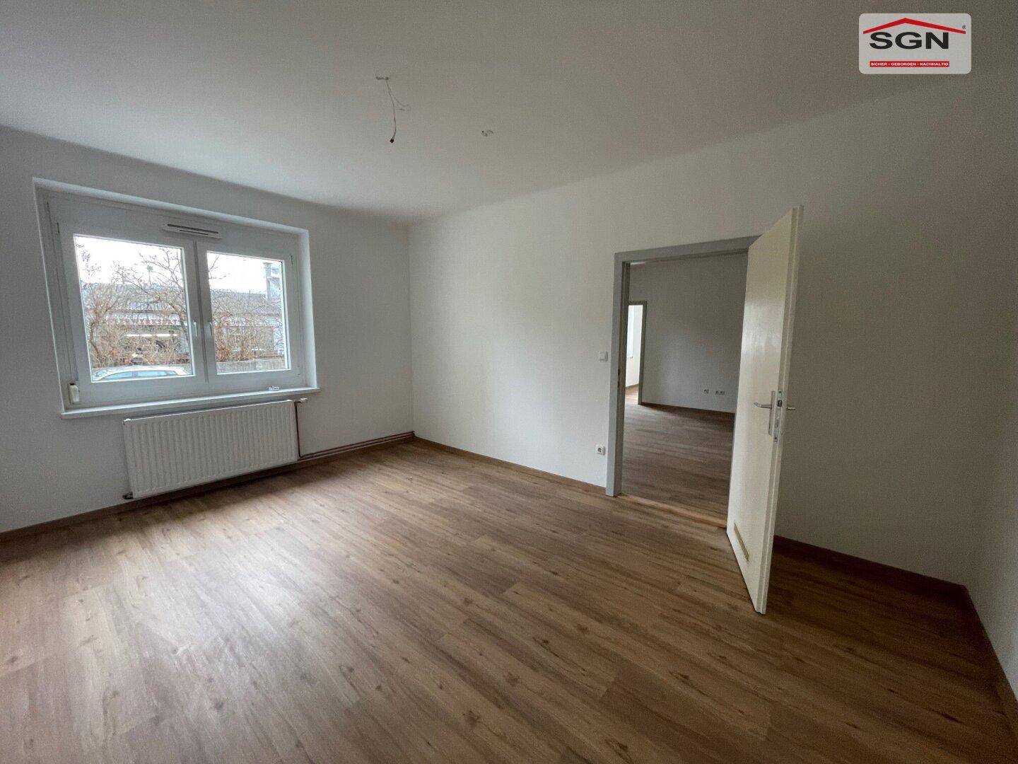 Geräumiges, unmöbliertes Zimmer mit Laminatboden und weiß gestrichenen Wänden, ideal für individuelle Gestaltung.