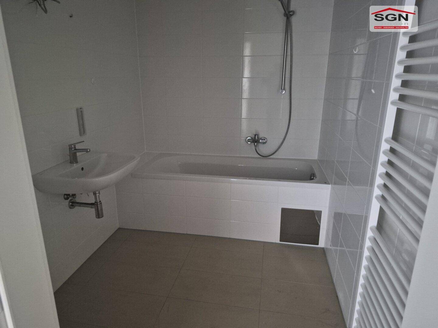 Modernes Badezimmer mit Badewanne, Dusche, Einzelwaschbecken und einem praktischen beheizten Handtuchhalter.