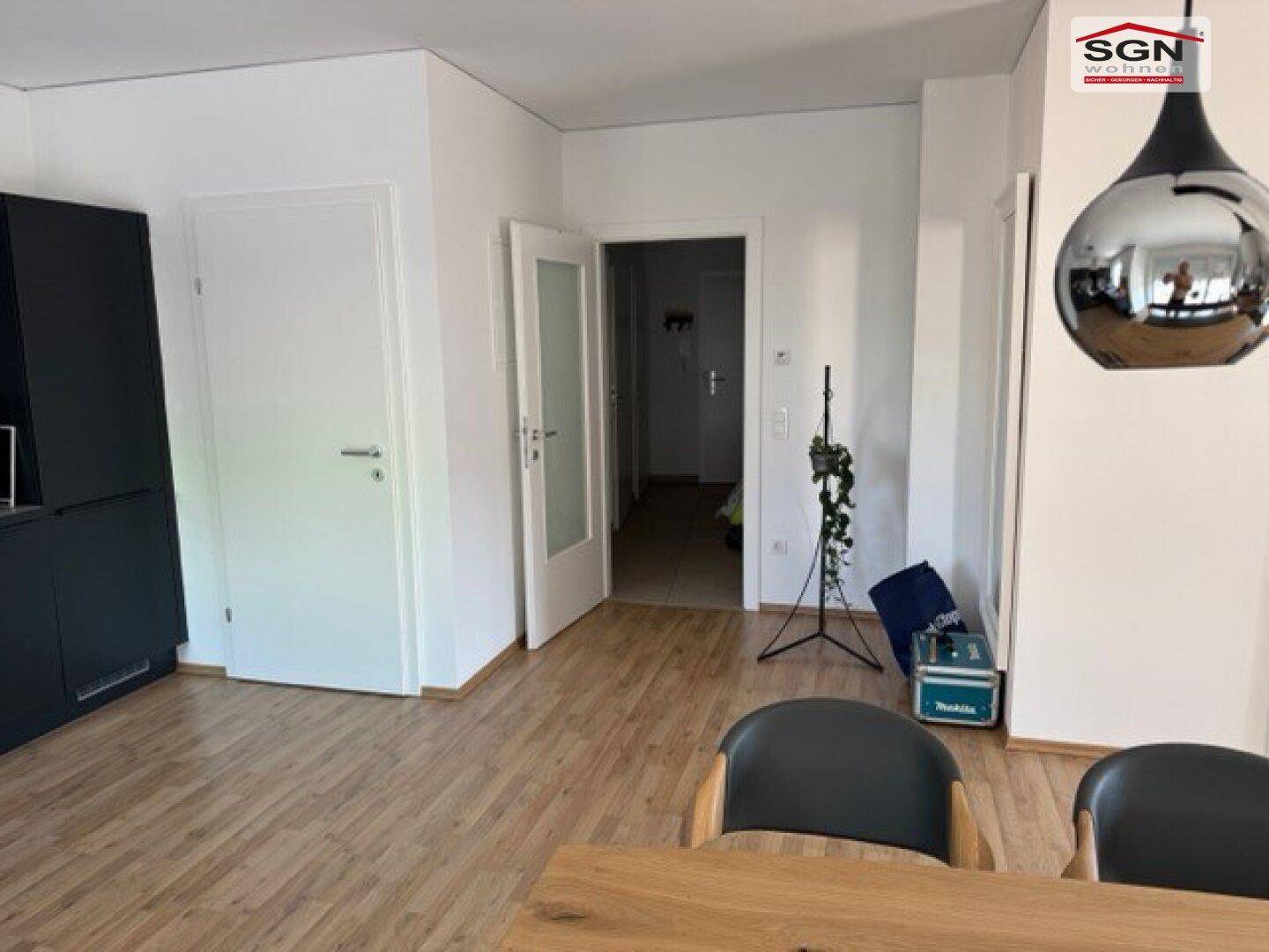 Heller Flur mit Holzboden, weißen Türen und Blick in den offenen Wohnbereich.