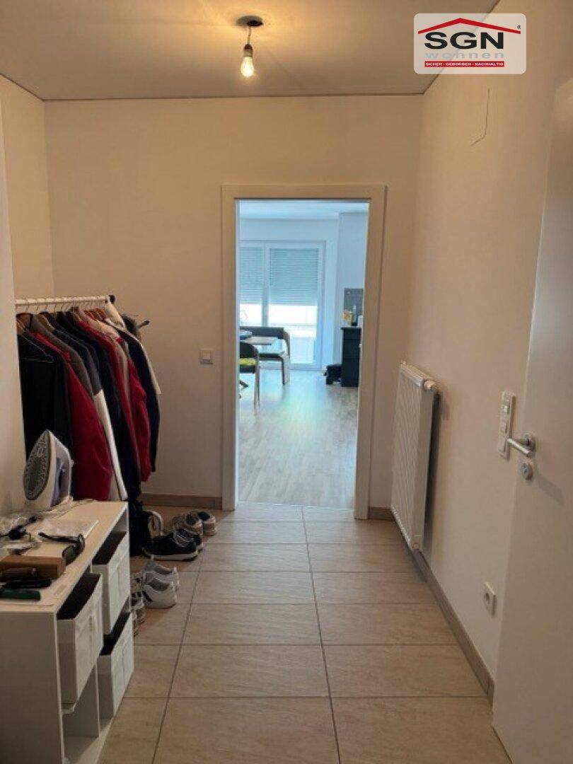 Flur mit Fliesenboden, Garderobe und Blick in den angrenzenden Wohnbereich.