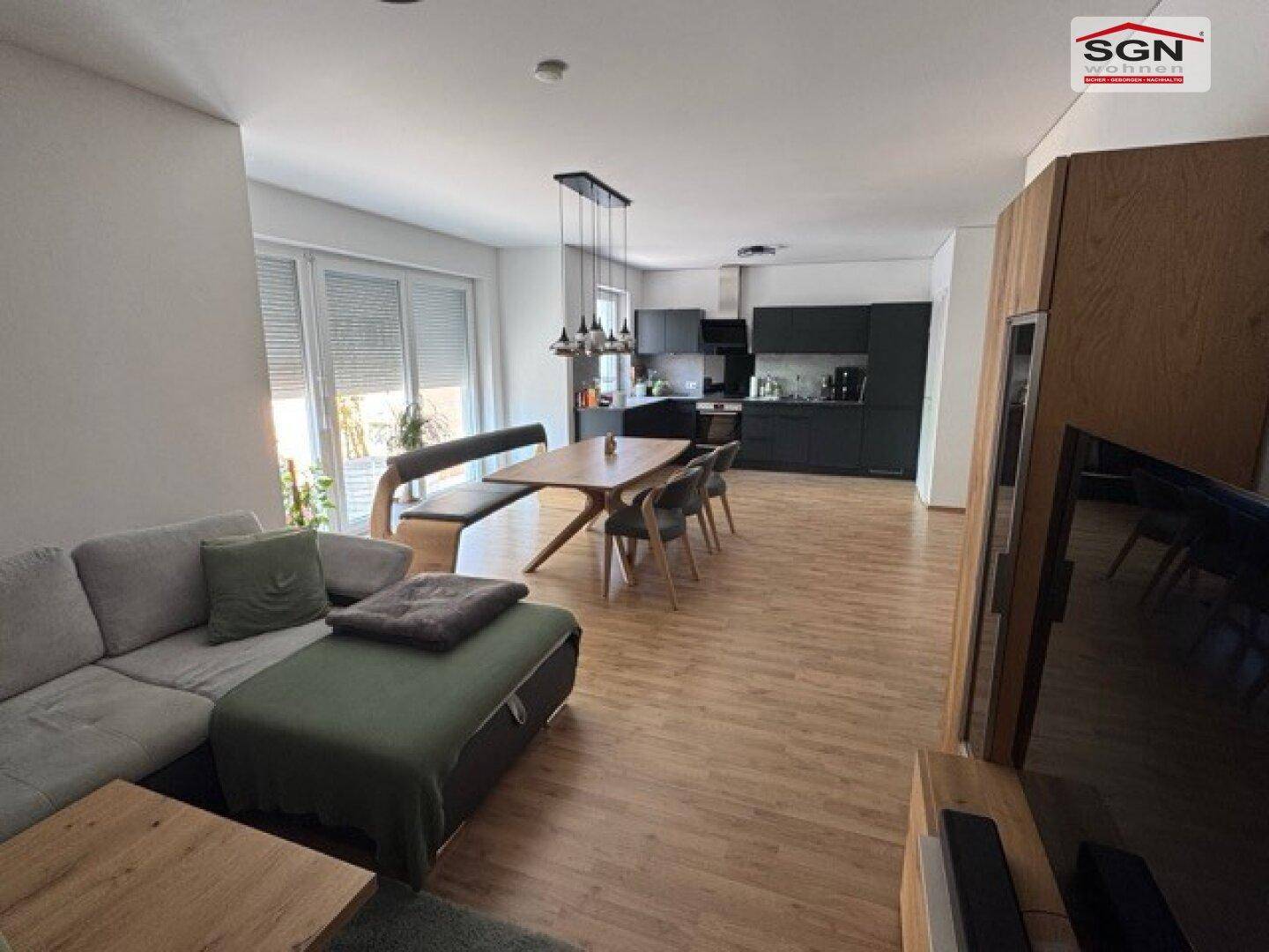 Weitläufiger Wohn-Essbereich mit offener Küche, Holzboden und viel Tageslicht.