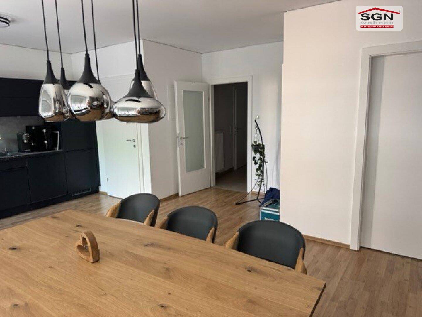 Essbereich mit Holztisch und modernen Pendelleuchten, angrenzend an den Flur.
