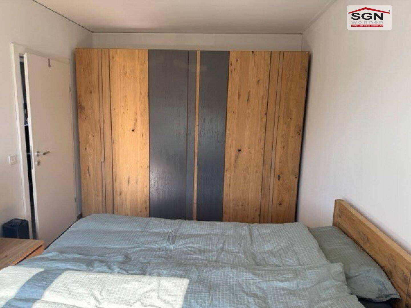 Schlafzimmer mit großem Holzkleiderschrank und Holzbett, das viel Stauraum bietet.
