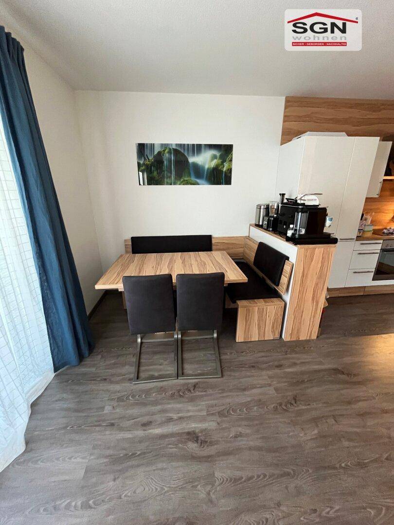 Gemütlicher Essbereich mit Holztisch, Eckbank und dunklen Stühlen neben der Küche.