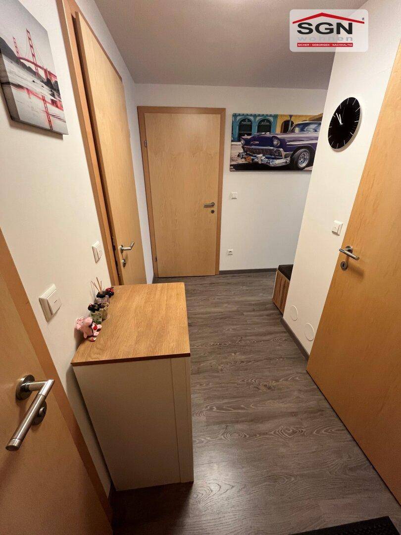 Heller Flur mit Laminatboden, Holztüren und dekorativen Bildern an den Wänden.