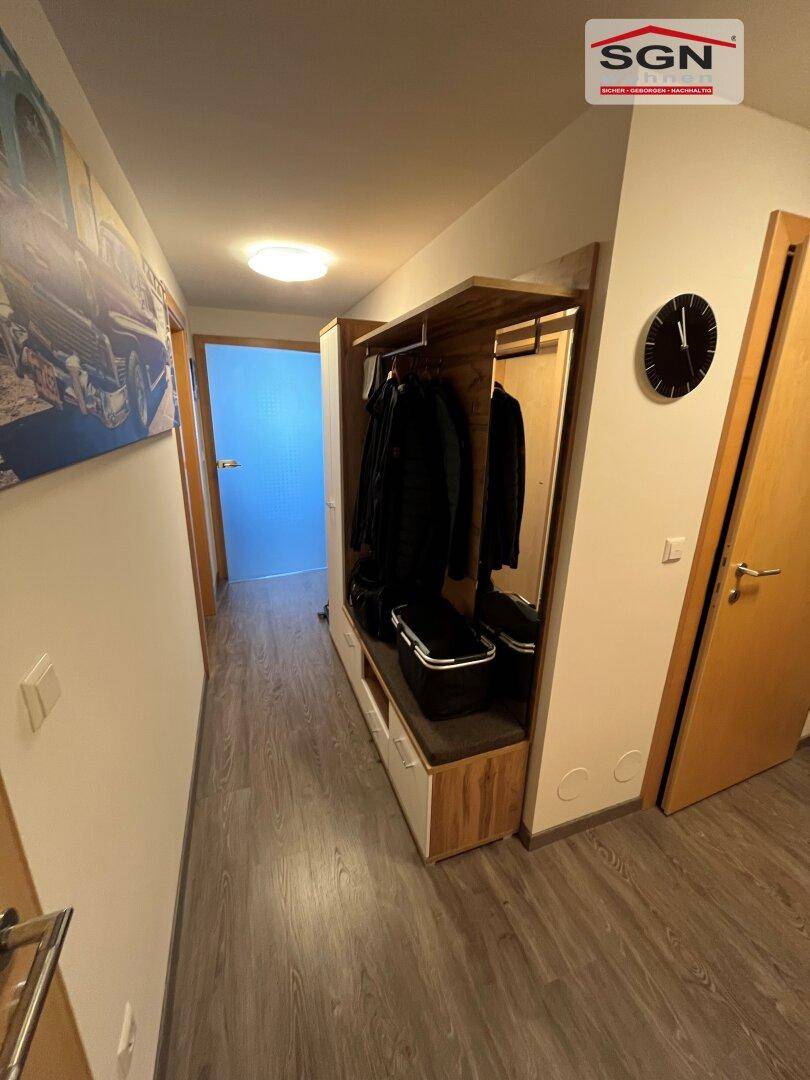 Geräumiger Flur mit Garderobe, Spiegel und Laminatboden in hellem Holzton.