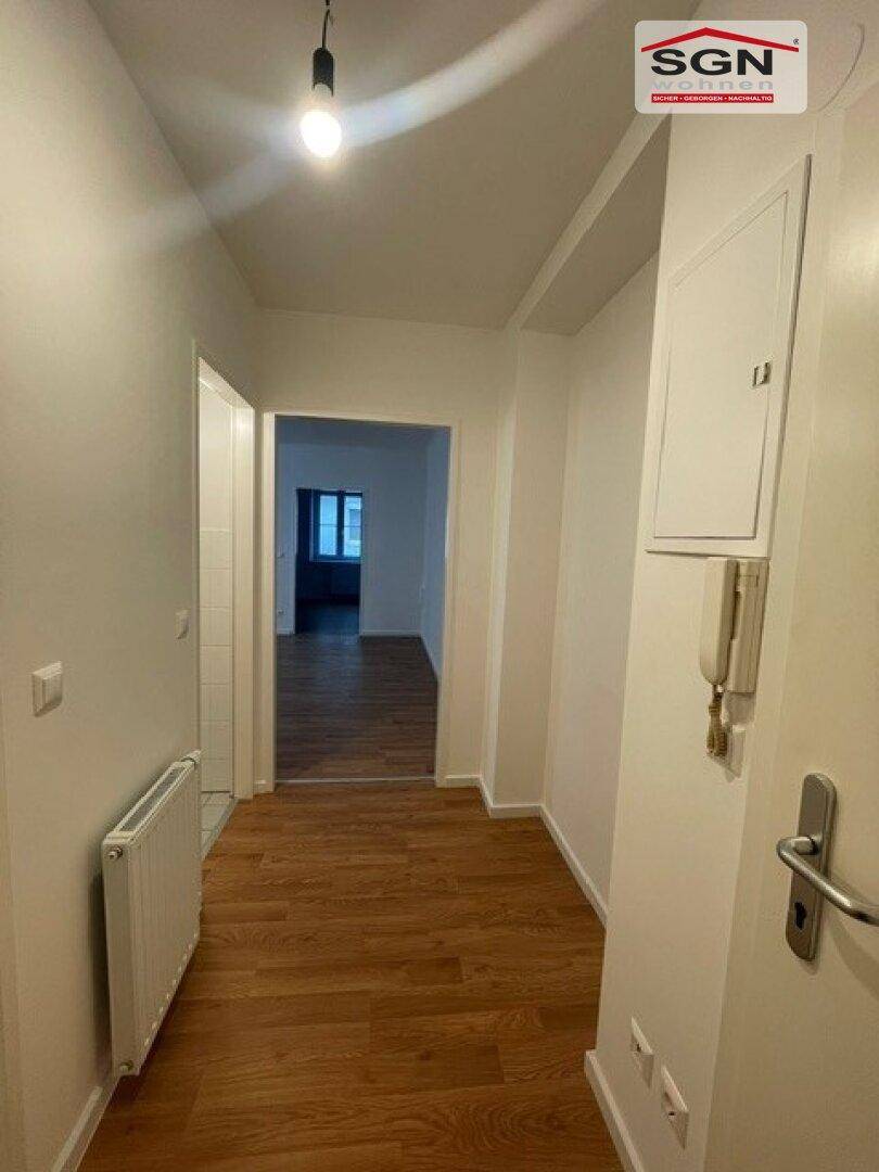 Heller Flur mit Holzfußboden und Blick in angrenzende Zimmer.