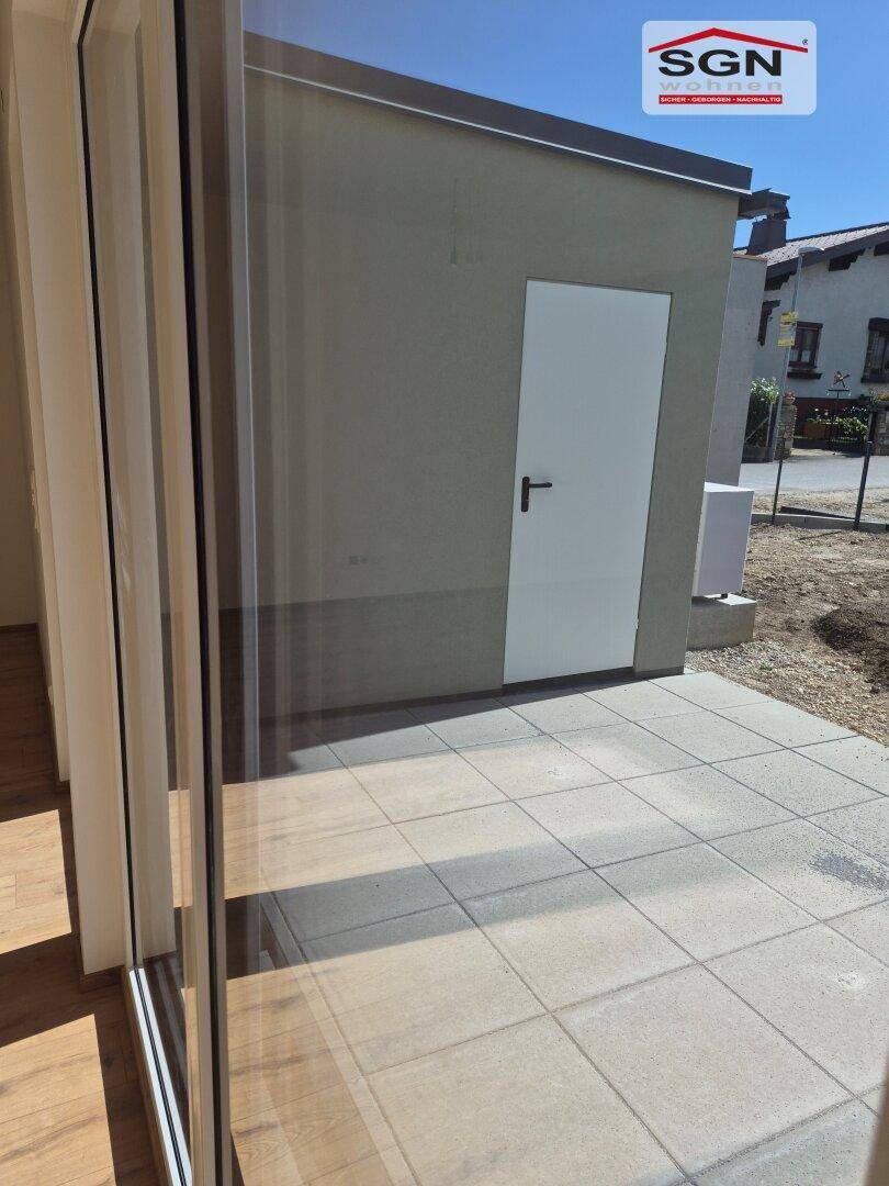 Gepflasterte Terrasse mit Zugang zum Gartenbereich und Blick auf die Umgebung.