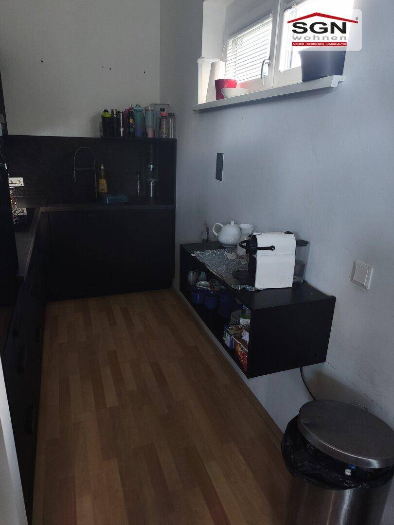 Küchenbereich mit schwebendem Regal, Fenster und hellem Laminatboden.
