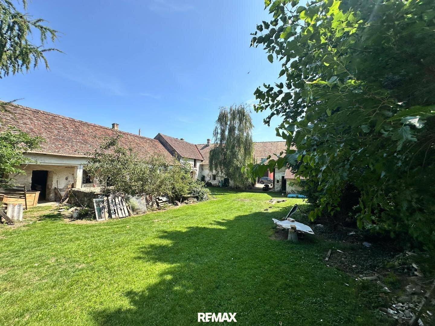 Großer, sonniger Gartenbereich mit Rasenfläche und Blick auf die historischen Hofgebäude.
