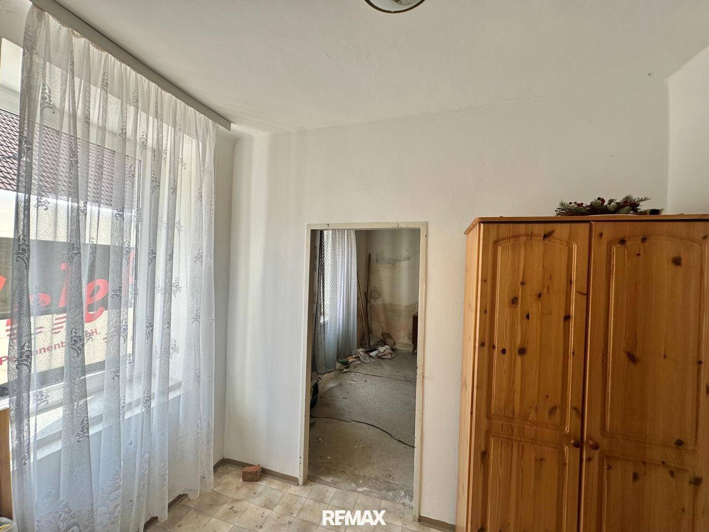 Zimmer in Renovierung mit Fenster und Blick auf die Baustelle im Nebenraum.