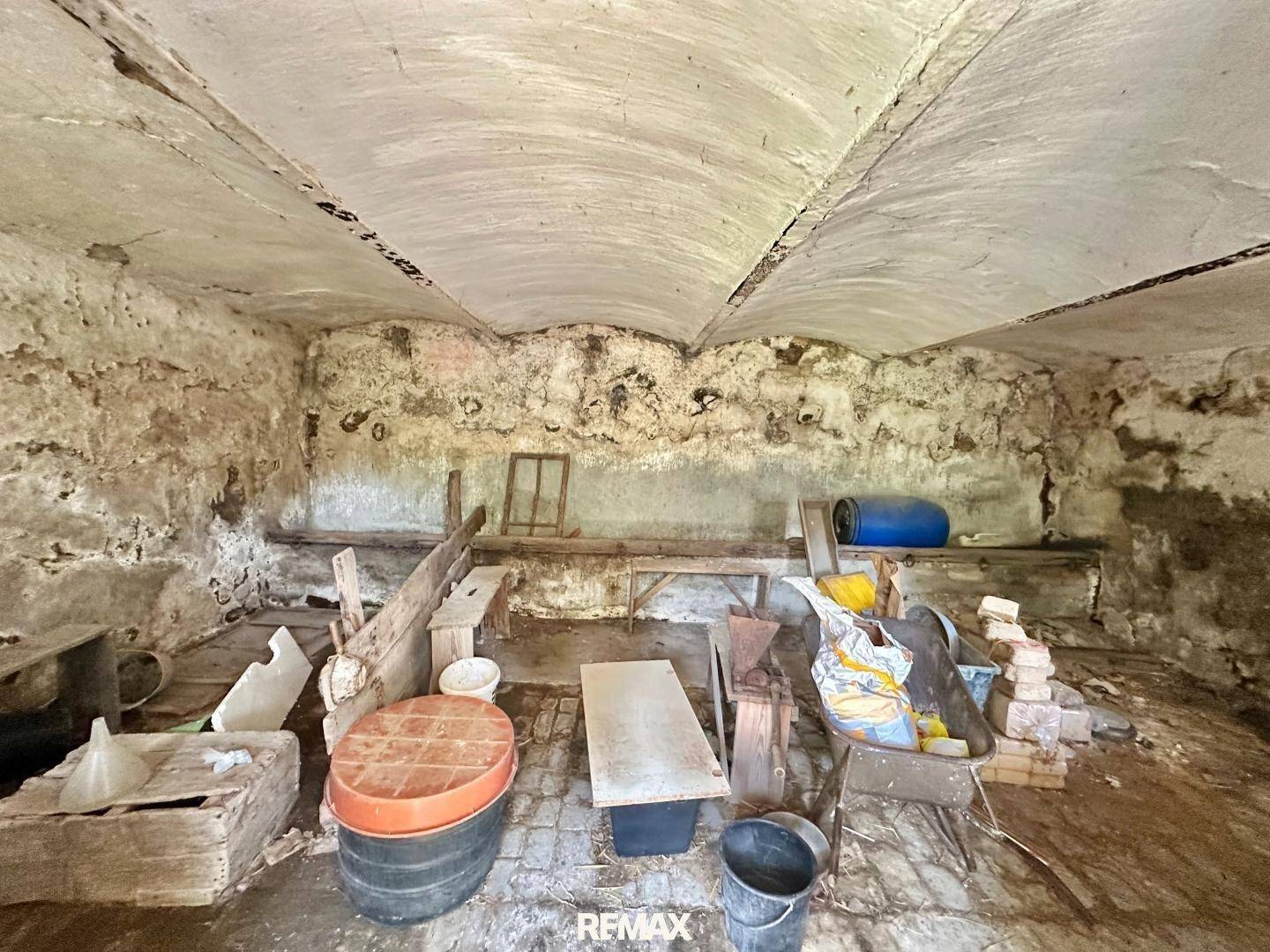 Alter Kellerraum mit gewölbter Decke, Steinwänden und verschiedenen Abstellgegenständen.