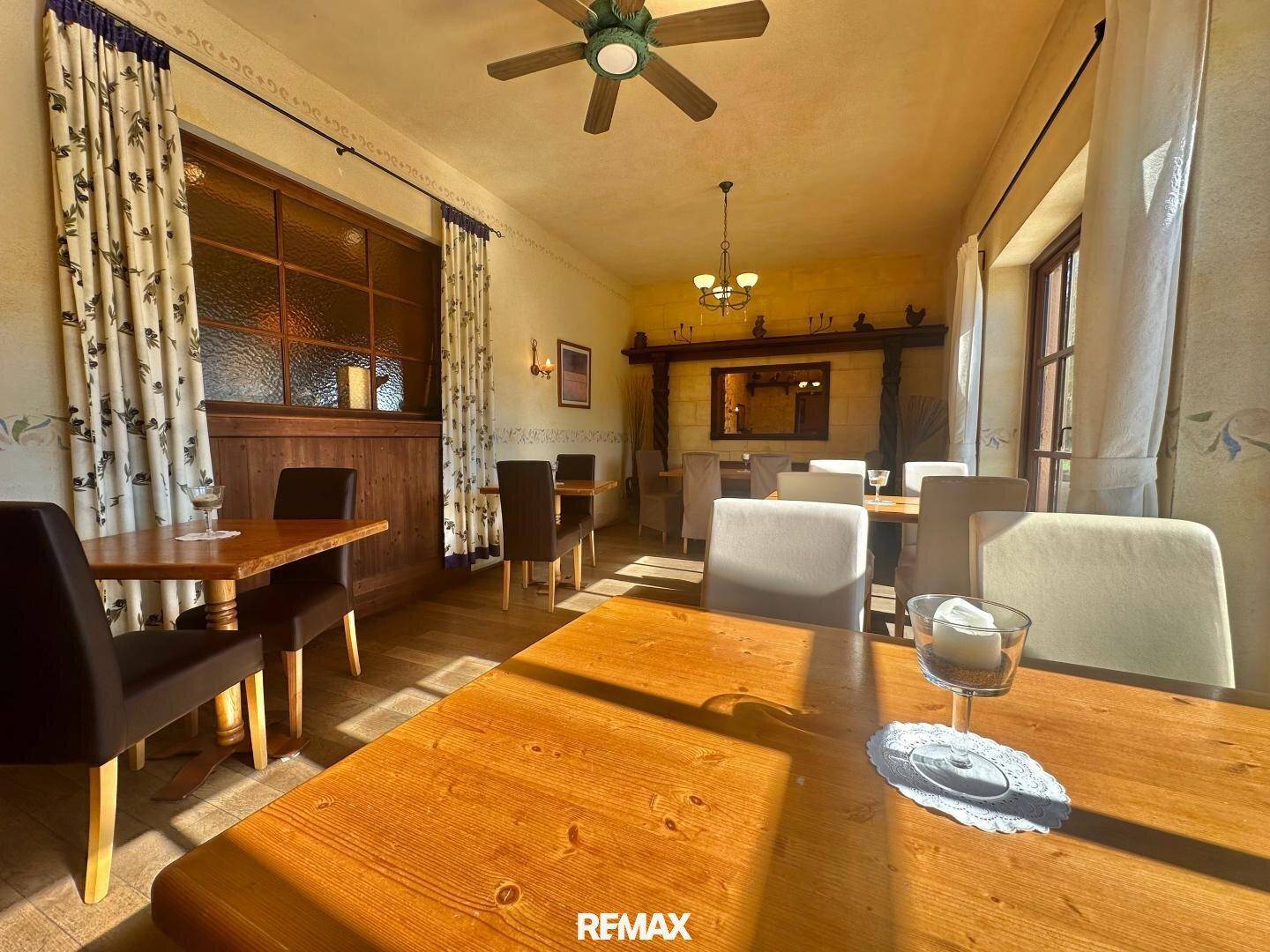 Heller Speisesaal mit Holztischen, bequemen Stühlen und einem Deckenventilator für angenehmes Klima.