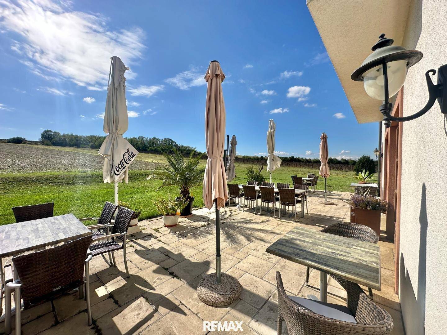 Weitläufige Terrasse mit mehreren Sitzbereichen und Sonnenschirmen, ideal für Mahlzeiten im Freien.