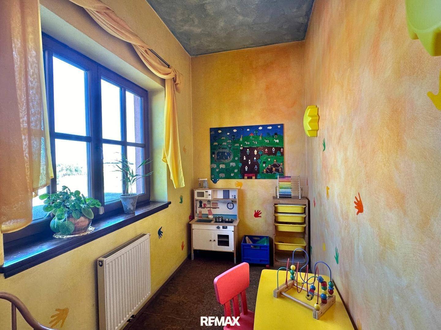 Farbenfrohes Spielzimmer mit gelben Wänden, Kindermöbeln und einem Fenster für natürliches Licht.