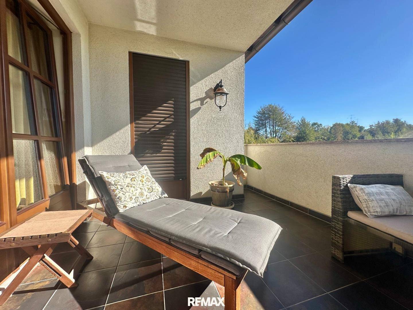 Heller Balkon mit Liegestuhl und Blick auf die grüne Umgebung, ideal zum Entspannen.