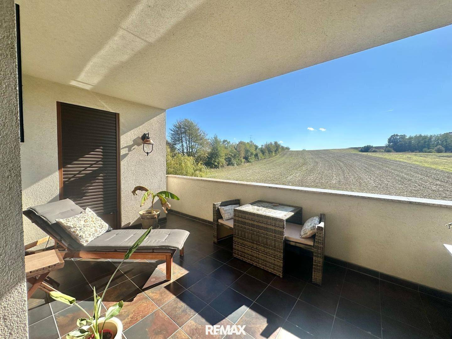 Sonniger Balkon mit Liegestuhl und Sitzgelegenheiten, bietet weite Ausblicke auf die Landschaft.