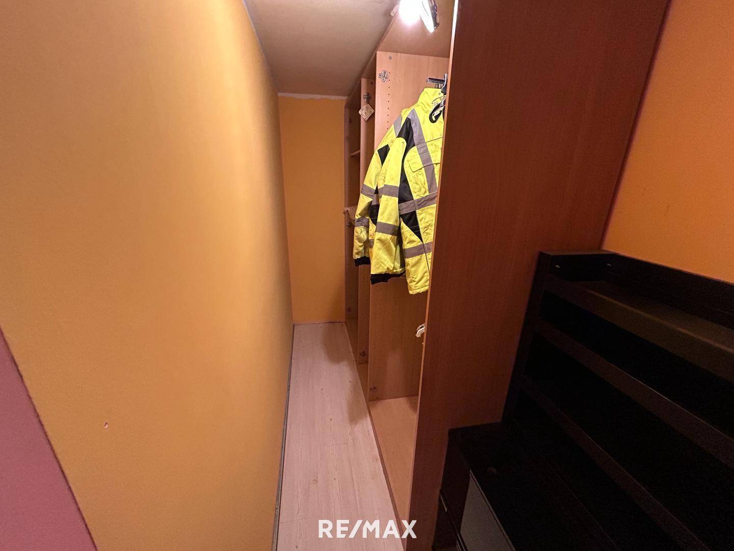 Kleiner Raum mit Regalen und Kleiderstangen, ideal als begehbarer Kleiderschrank oder Abstellraum.