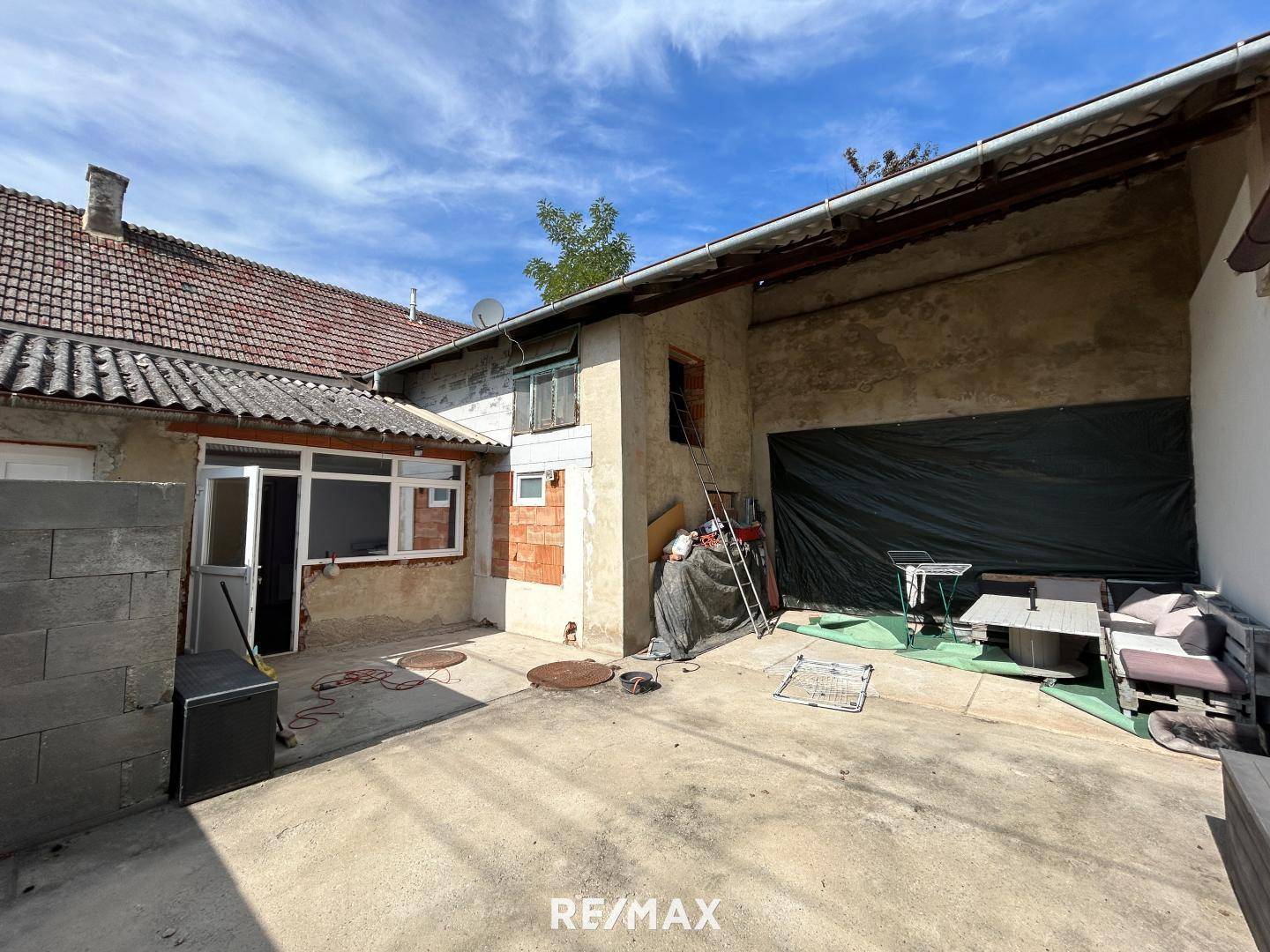 Hinterhof mit gepflastertem Bereich und Gebäuden, die Renovierungsbedarf aufweisen.