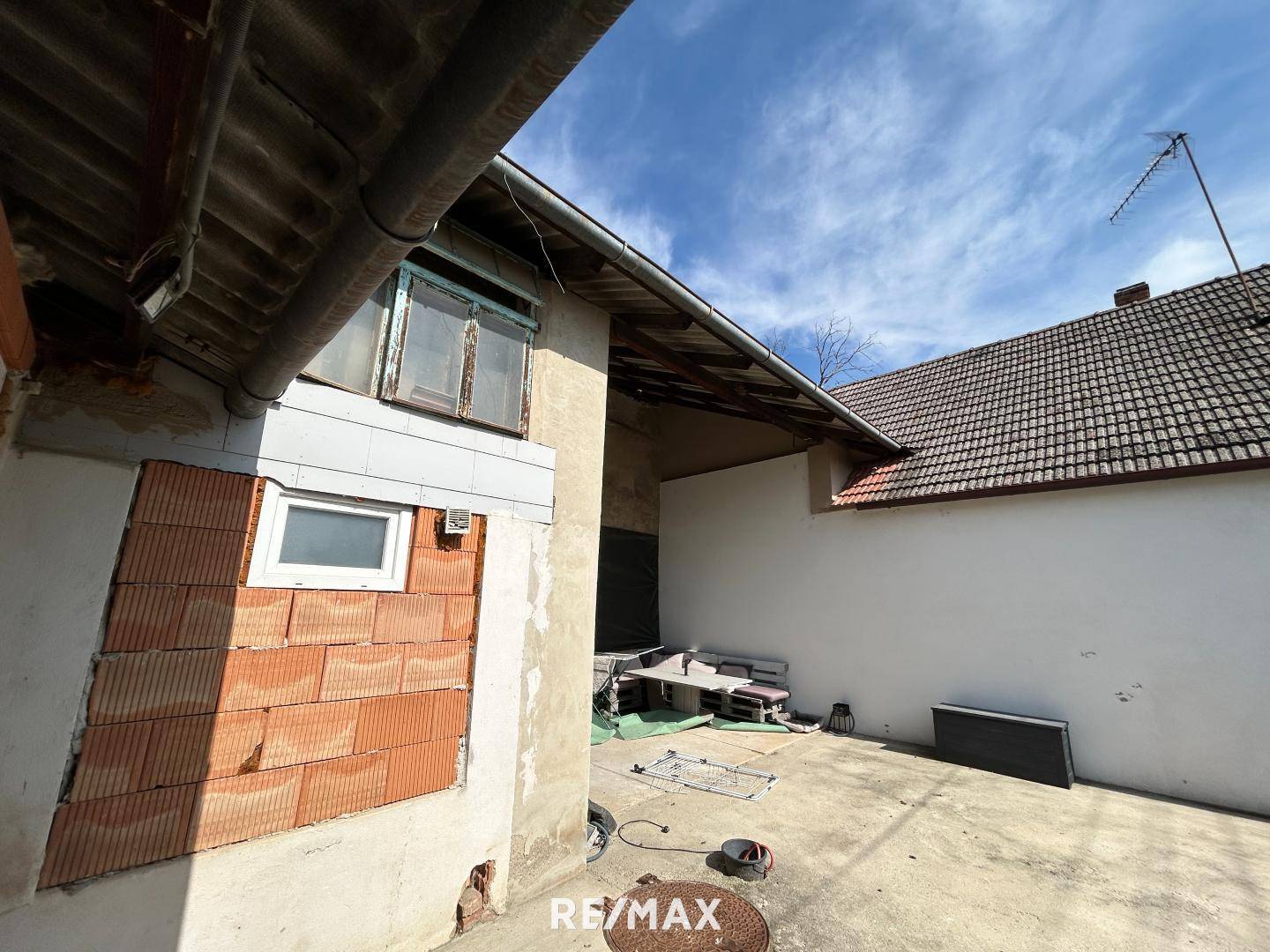 Hinterhof mit gepflastertem Bereich und Gebäuden, die Renovierungsbedarf aufweisen.