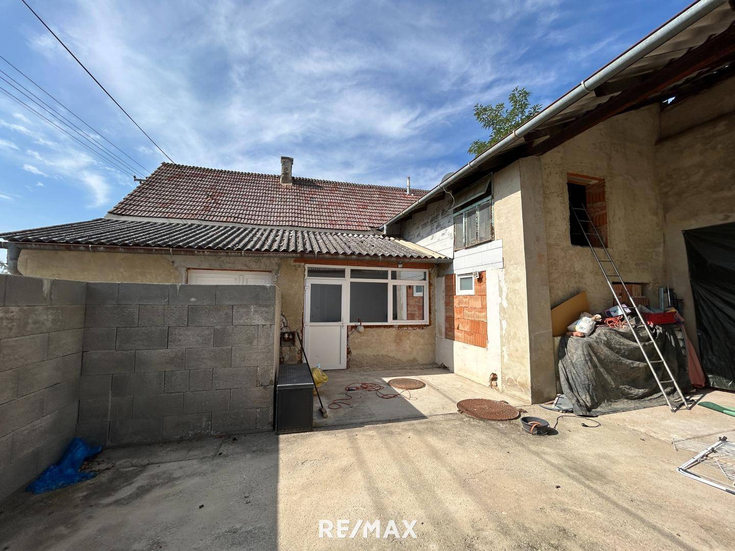 Hinterhof mit gepflastertem Bereich und Gebäuden, die Renovierungsbedarf aufweisen.