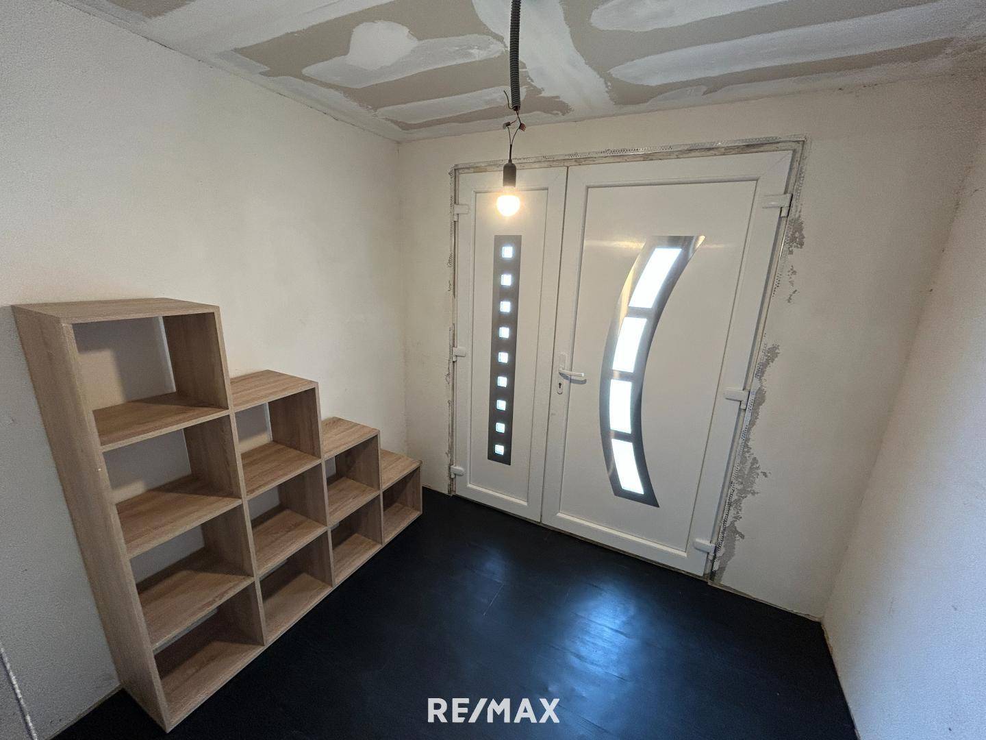 Eingangsbereich mit doppelter Eingangstür und Regalsystem, derzeit in Renovierung.