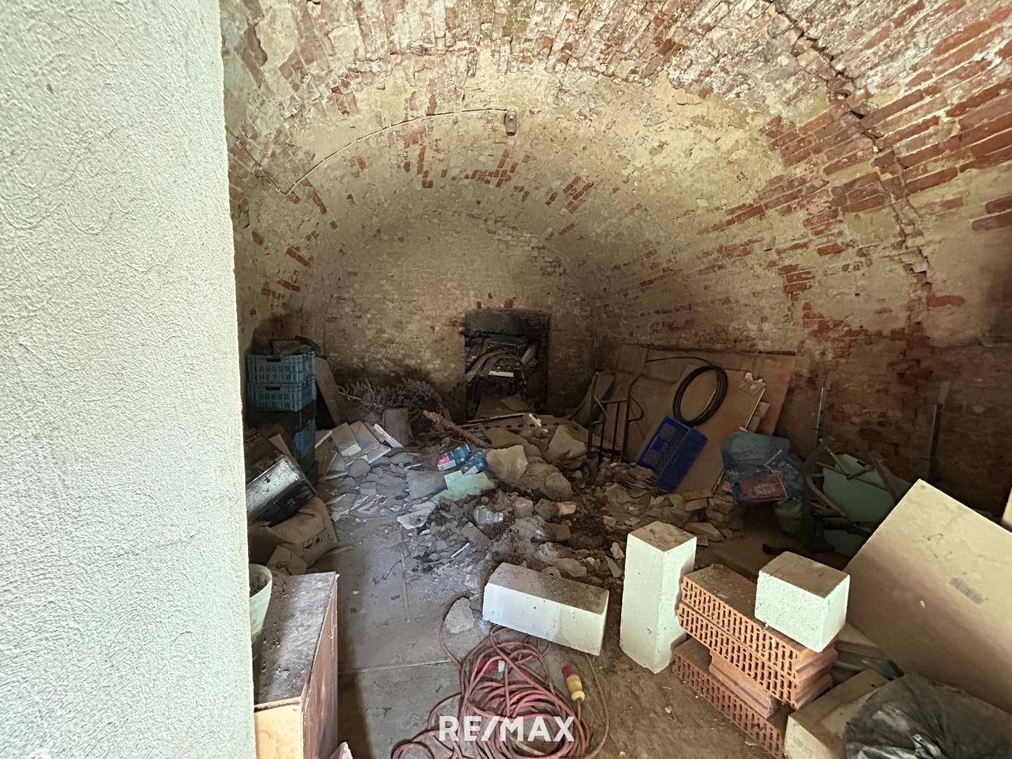 Alter Keller mit gewölbter Ziegeldecke und Wänden, der als Abstellraum genutzt wird und Renovierung benötigt.