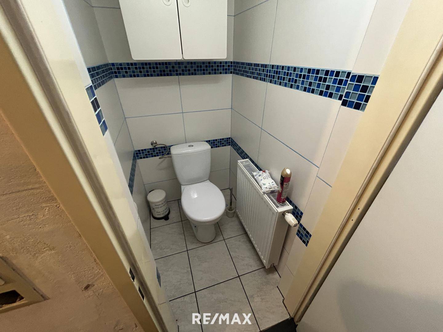 Kleines Gäste-WC mit Fliesen, Toilette und Heizkörper.