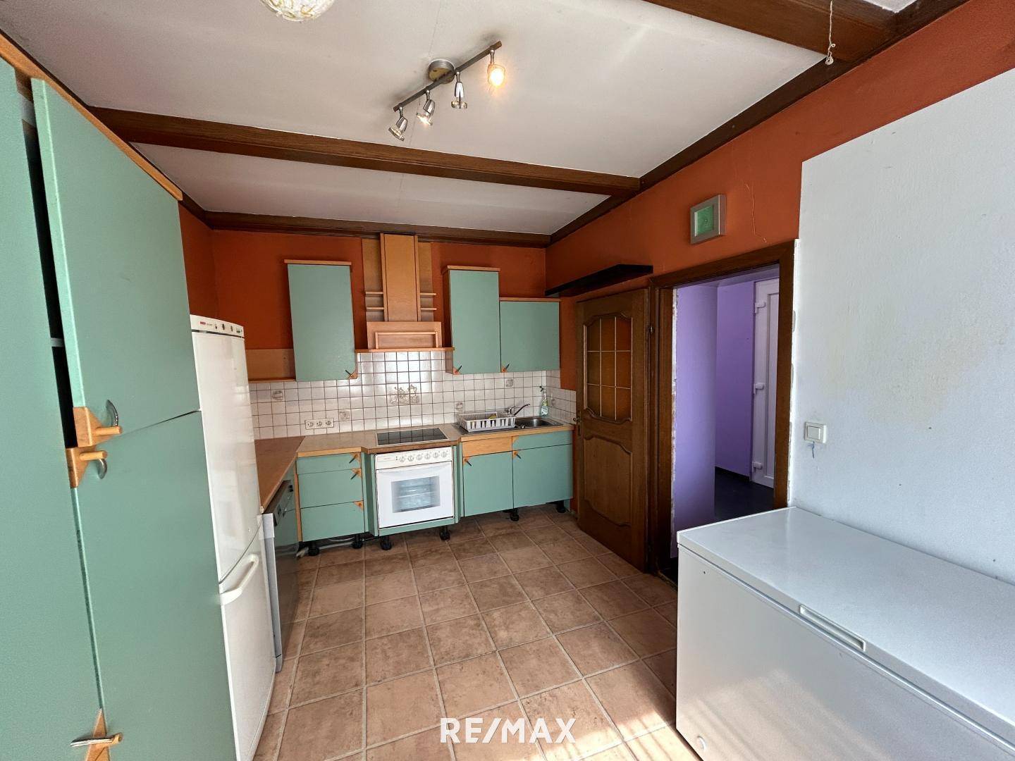 Küche im traditionellen Stil mit mintgrünen Schränken, Terrakotta-Fliesen und sichtbaren Holzbalken.