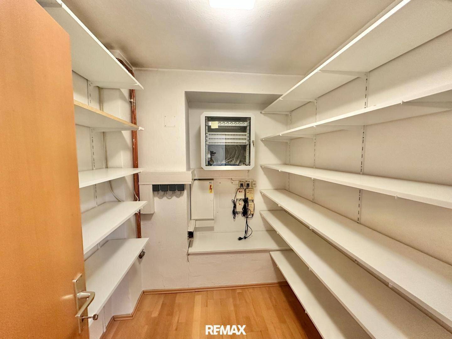 Geräumiger Abstellraum mit vielen weißen Regalen an beiden Seiten, ideal für Lagerzwecke.